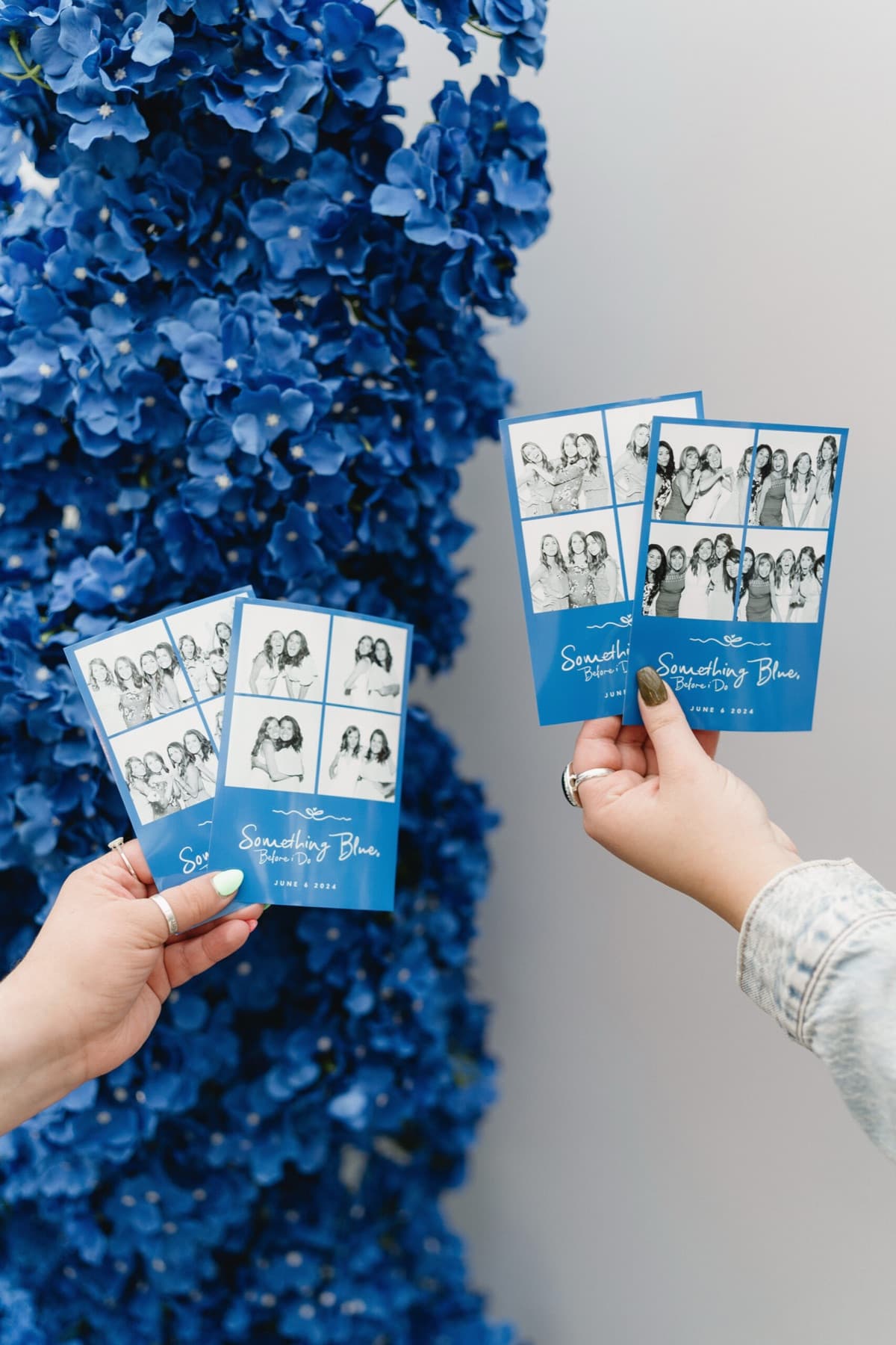 Hands holding 'Something Blue' photo strips in front of a blue hydrangea wall.