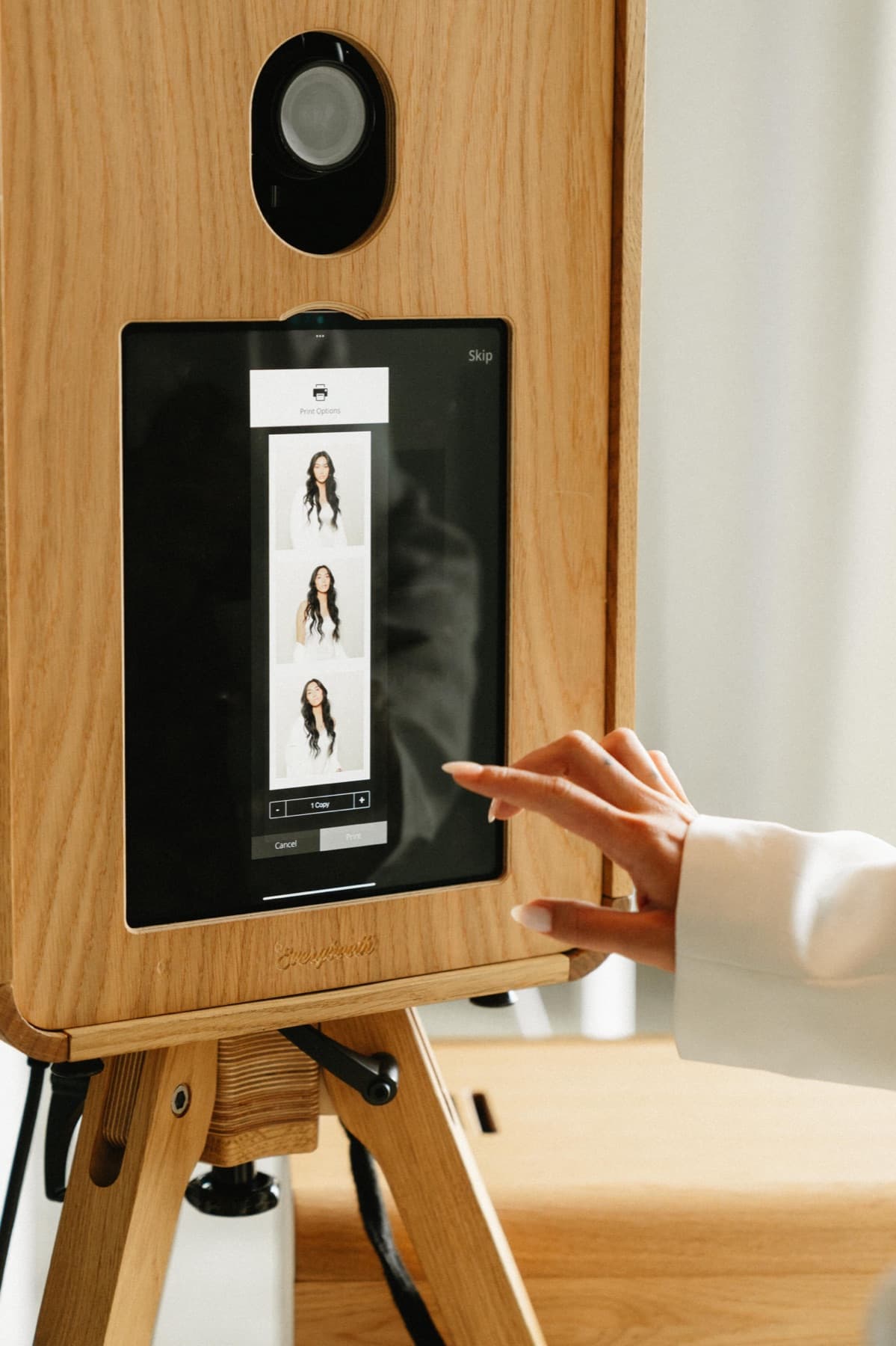 A close-up of the MEMORI booth touchscreen showing print options for a three-frame photo strip.