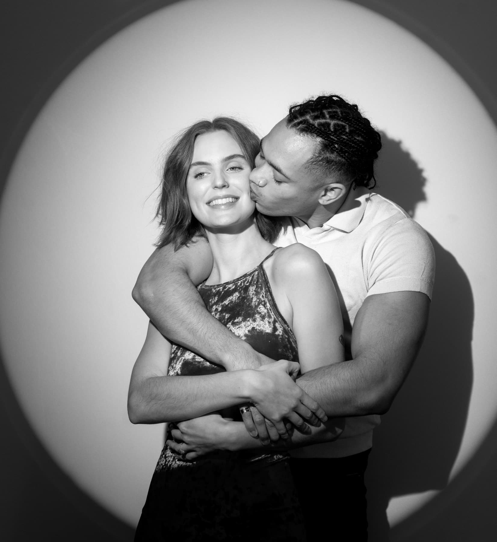A black-and-white spotlit portrait of a couple embracing in the MEMORI booth — the quiet, genuine emotion at the heart of every event.