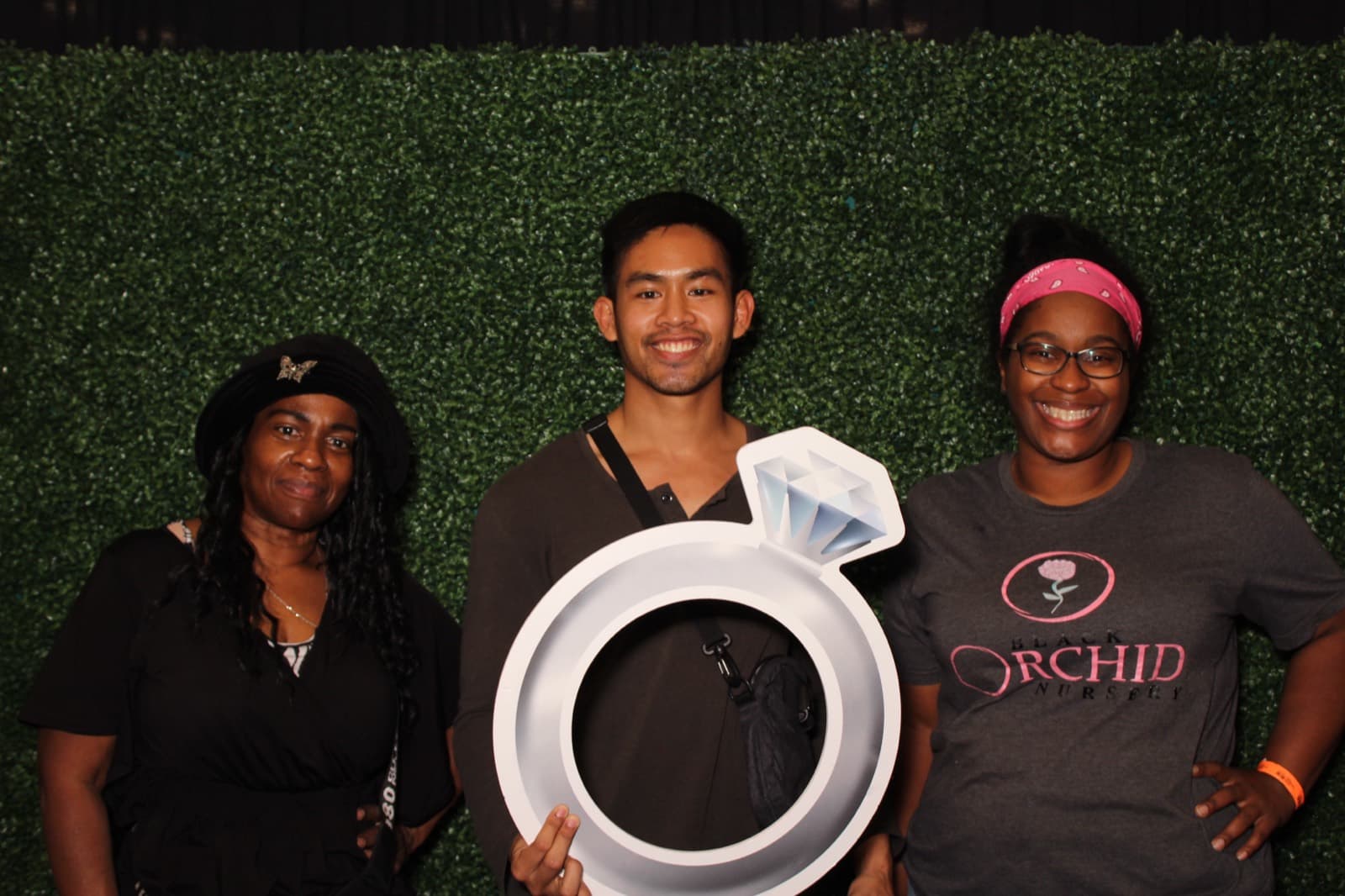 Thomas posing with guests in front of a greenery wall backdrop.