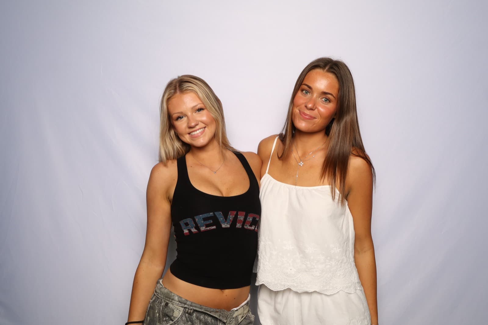 Two best friends smiling side by side in front of a white backdrop.