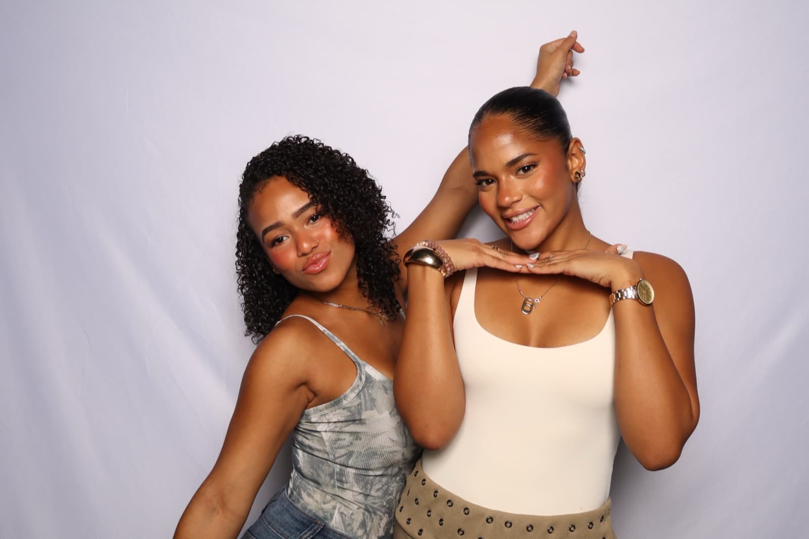 Two friends striking a pose together in front of a white backdrop.