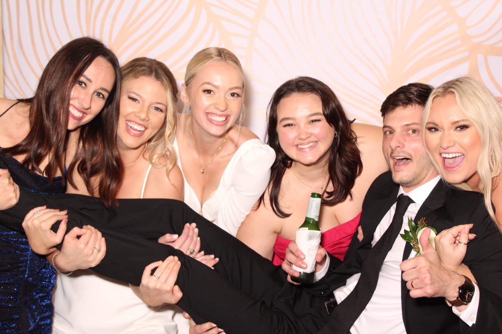 Wedding guests laughing together in front of a blush floral backdrop.